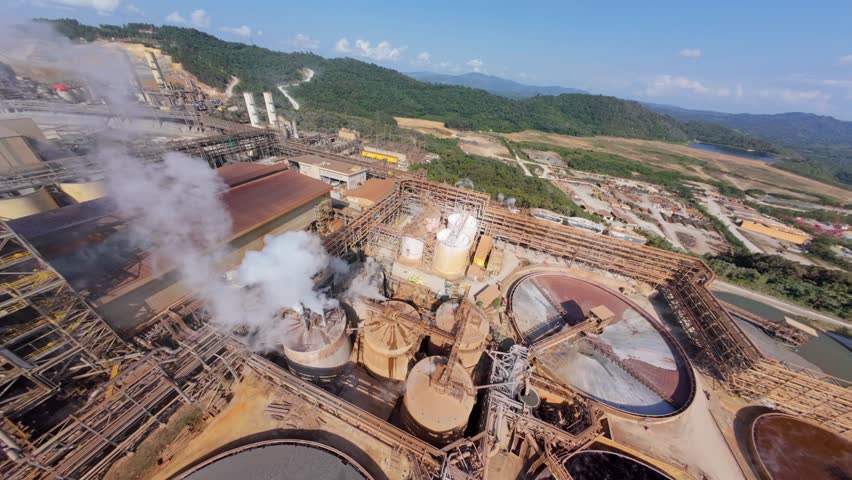 FPV aerial around gold refinery factory with white smoke and large clarifier