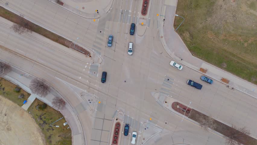 Overhead drone shot of cars moving through a modern city intersection in Winnipeg, Canada, showing infrastructure, vehicle flow, and urban layout.