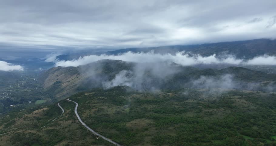 Drone view of foggy landcape of mountains with clouds on top during dawn in Cetinje, Montenegro.