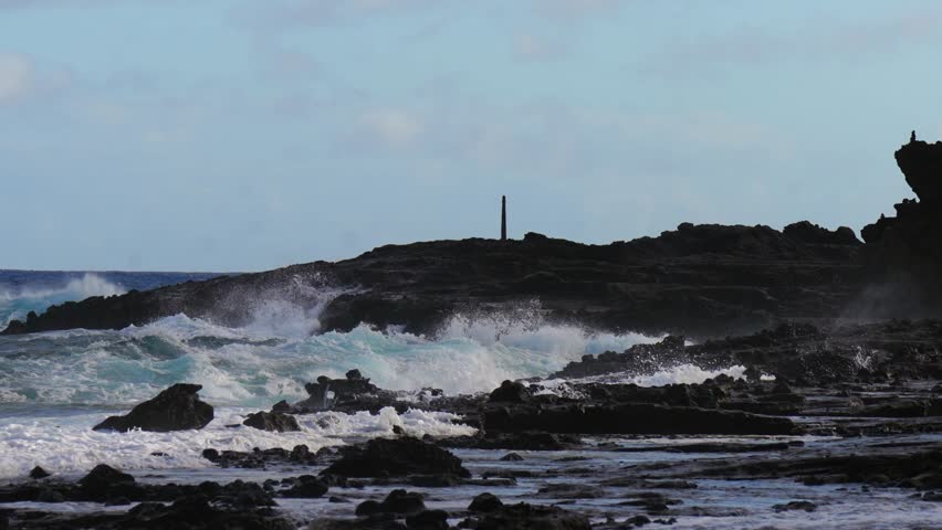Dramatic waves crash against the rocky coast at Halona (lookout) Blowhole as powerful surf forces seawater to spout high into the air, showcasing Hawaii