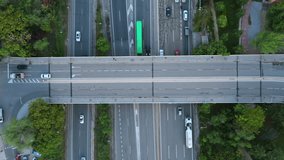 Vertical drone shot capturing fluid traffic on a busy highway interchange and overpass. Vehicles smoothly passing on multiple lanes, surrounded by lush greenery, emphasizing urban transportation - Powered by Shutterstock - Get 15% off with code: PIKWIZARD15