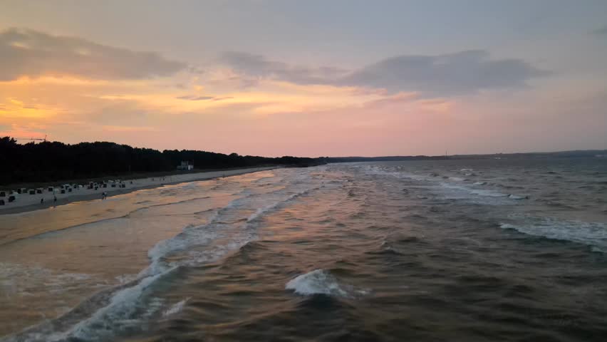 Sunset over the Baltic Sea at Prora beach on Rügen Island, with waves rolling in and soft evening light painting the sky in warm tones.
