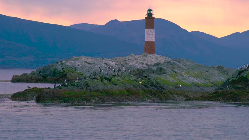 Les Eclaireurs Lighthouse on a rocky island with cormorants in the Beagle Channel near Ushuaia, Argentina at sunset. Aerial drone view.