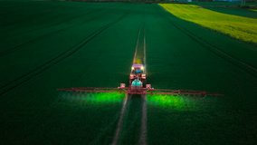 Farming tractor spraying wheat field at night with lights on. Tractor illuminating field while spraying wheat crops with fertilizers and pesticides. Spraying wheat field using farming tractor with - Powered by Shutterstock - Get 15% off with code: PIKWIZARD15