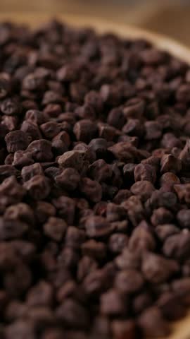 Raw Dark Brown Chickpeas (Kala Chana) on a rustic wooden table. Dry Balck chickpea (ceci neri) background close up.