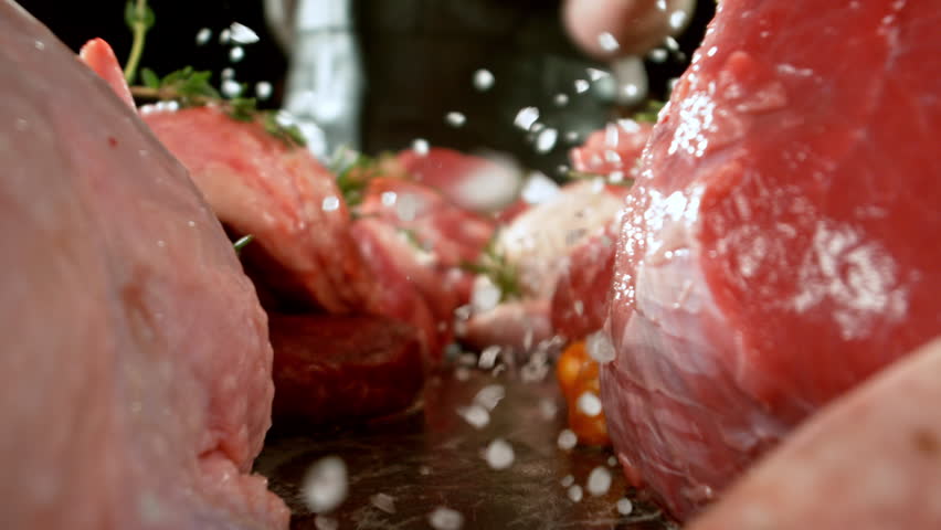 Slow motion, camera move. Large assortment of premium raw meat, beef, sausages, pork and chicken suitable for butchery advertising, fire on background