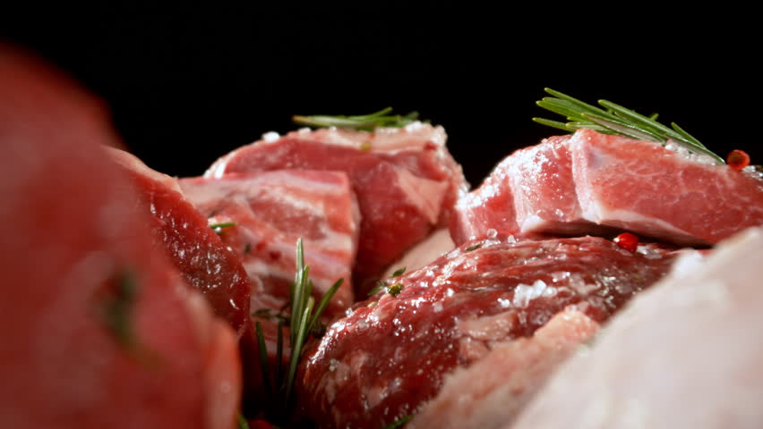 Slow motion, camera move. Large assortment of premium raw meat, beef, sausages, pork and chicken suitable for butchery advertising, fire on background