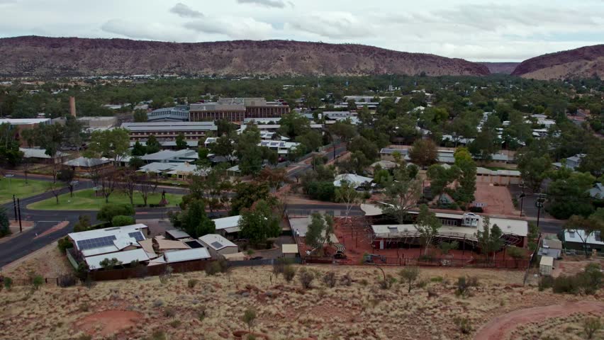 Rising drone footage of Alice Springs, looking south towards the MacDonnell Ranges and Heavitree Gap, Alice Springs, Mparntwe, Northern Territory, Australia. August 2022.