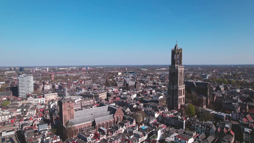 Cityscape aerial of city center Utrecht, The Netherlands, on a bright sunny day with church and cathedral rising above the low build picturesque canal homes. Urban development and Dutch flat landscape