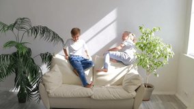 Small active boy and girl jumping barefoot on sofa in cozy warm living room, charming children siblings or friends having playful funny mood play together at home, kids hyperactivity concept - Powered by Shutterstock - Get 15% off with code: PIKWIZARD15