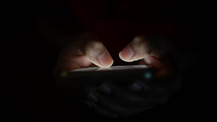 Close up of young man hand using smart phone at night 