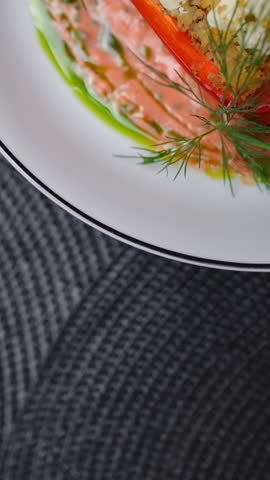 Vertical footage Gourmet stuffed bell pepper with feta, cherry tomatoes, and couscous, garnished with dill on white plate, featuring creamy sauce