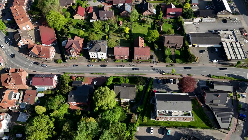 Traffic scene on street in german city with townhouses and green trees in spring. Sunny day in historic town. Aerial top down flyover shot.
