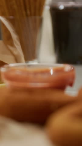 Vertical close-up shot of unrecognizable hand dipping bunch of delicious french fries into ketchup