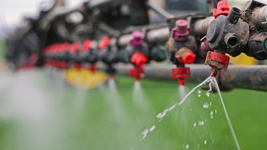 Close-up of sprayer nozzles releasing liquid onto crops, Precision agriculture equipment spraying fertilizer in fine jets