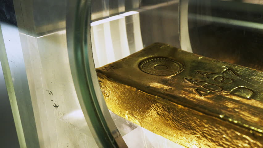 Macro shot of a heavy fine gold bar, resting in a bank or safe, symbolizing high value, investment, or wealth.