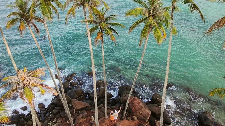 Aerial static exited romantic tourist couple standing on Coconut Tree Hill viewpoint Overlooking the Indian Ocean in Sri Lanka. Romantic escape concept. Idyllic scene love, connection, serenity