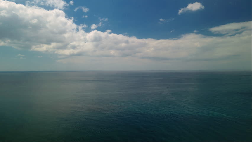 Quiet azure sea water surface under blue sky with fluffy clouds in morning aerial view. Spellbound marine view with clear ocean and cloudscape. Inspiring ocean journey on vacation
