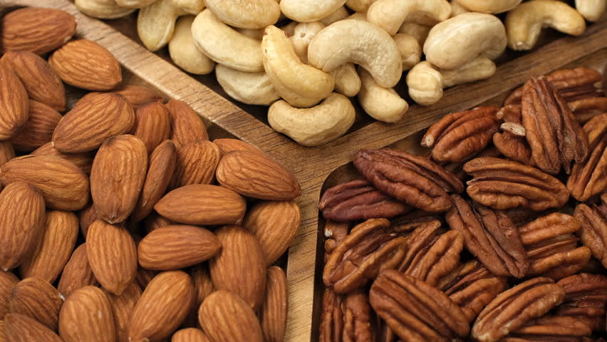 Dried different type of nuts in wooden plate, rotation