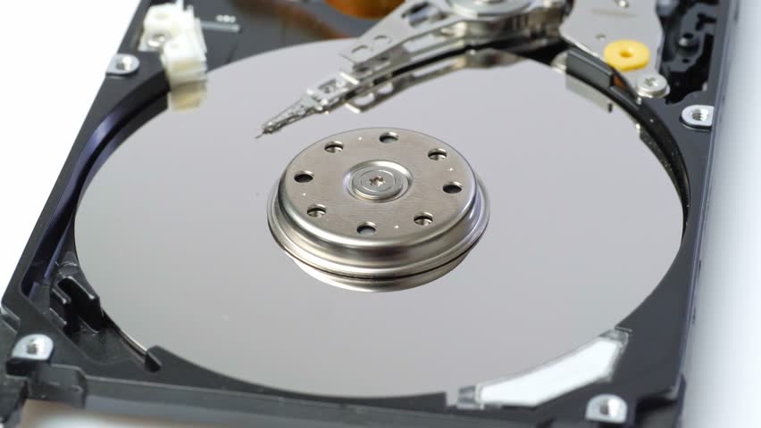 A detailed view of an opened laptop hard disk drive (HDD), revealing its internal components. The shiny, circular platter, the head assembly, and the actuator arm are clearly visible