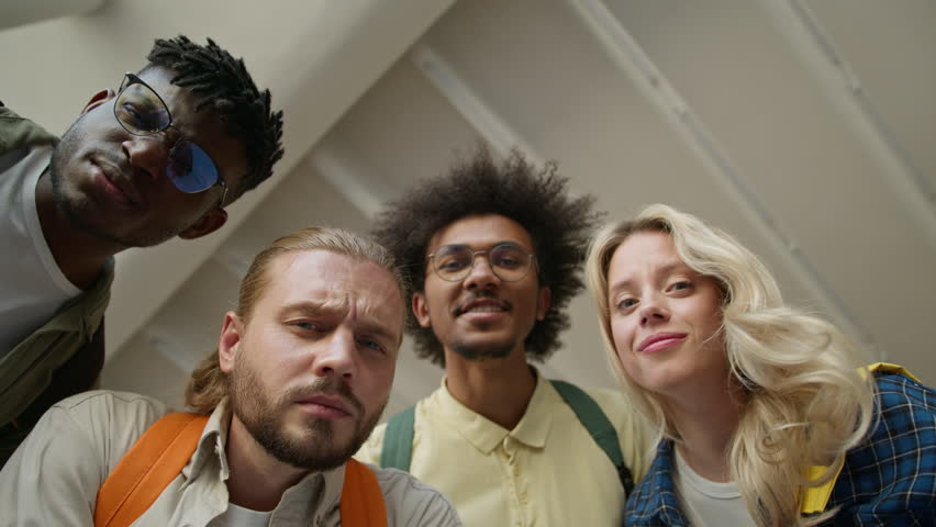Bottom view faces of multiracial students confusion diversity friends African American men guys males Caucasian woman girl female looking together at camera confused puzzled emotions in university