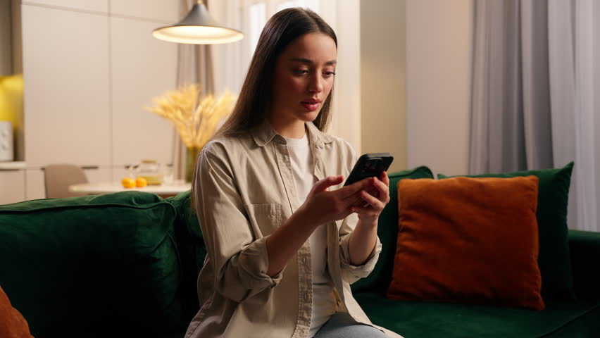 Disappointed stressed upset emotional despair Caucasian woman looking at mobile phone device at home living room failure lose game frustrated female girl with smartphone scam message bet loss error