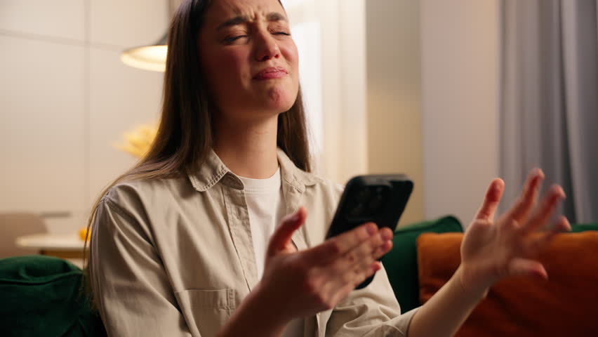Disappointed stressed upset emotional despair Caucasian woman looking at mobile phone device at home living room failure lose game frustrated female girl with smartphone scam message bet loss error