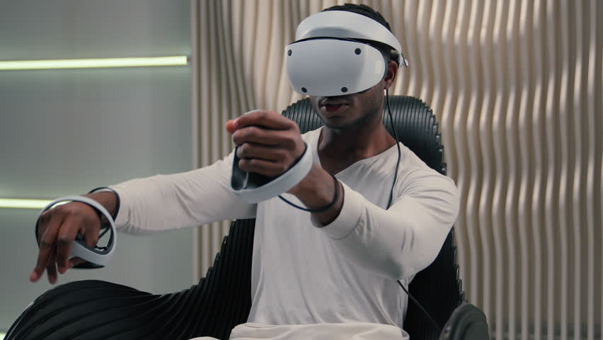 African American gamer guy male man wearing virtual reality headset indoors playing interactive game with motion controllers immersive digital experience modern technology futuristic entertainment - Powered by Shutterstock - Get 15% off with code: PIKWIZARD15