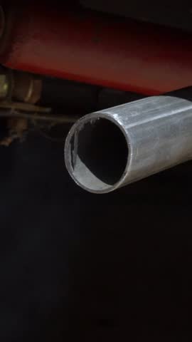 Vertical Slowmotion closeup combustion fumes coming out of car exhaust pipe which strongly of white smoke. Poisonous carbon monoxide from vehicle on road, air pollution concept. Fume emissions traffic