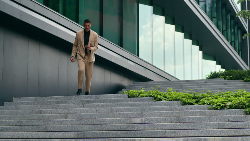 African American investor businessman man guy male business worker manager walking fast stairs down in city outdoors office building leaving rejoice good result work success yes gesture achieve smile