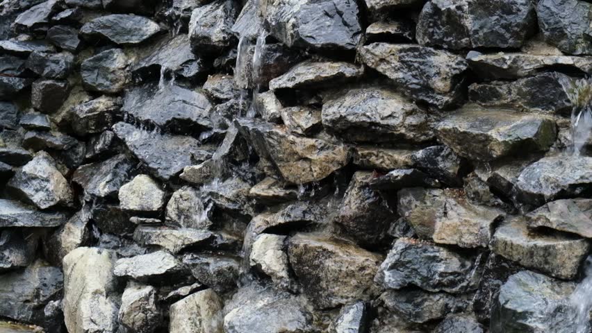 Rock wall Mountain river falls Waterfall flows down from cliff with splashes. Water falling pouring from stone wall close up. Background with running water. Waterfall fountain spray drops stone