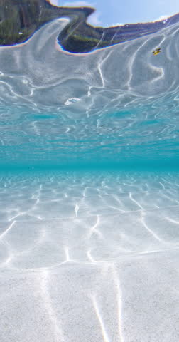Transparent ocean with white sand bottom underwater, blue sea in sunny day