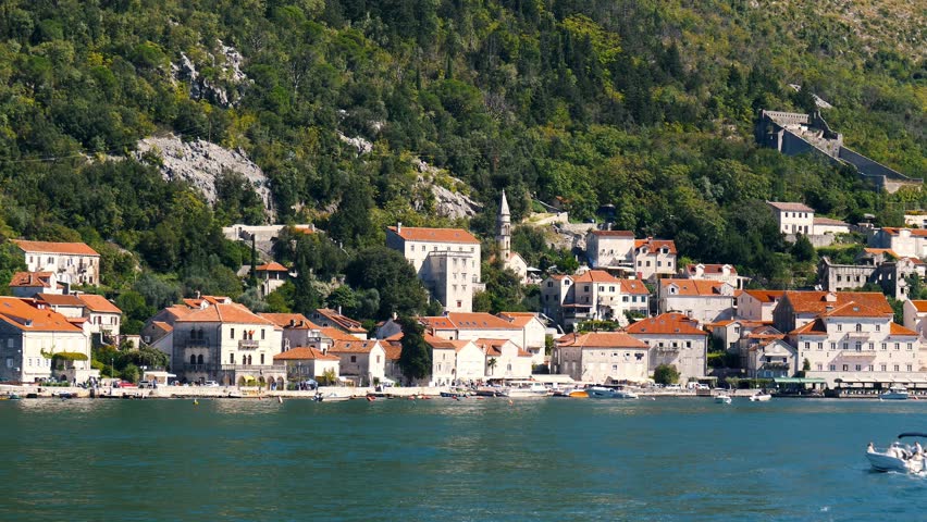 Picturesque perast town located on bay of kotor in montenegro, presents its charming architecture and serene coastal beauty. Motorboat gracefully navigates tranquil waters