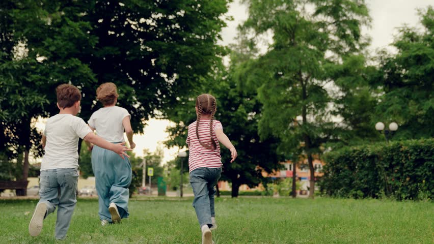 Mother, child, girl, boy, play, run on green lawn in summer park. Family vacation. Happy running children, boy, girl, mother in nature. Weekend with family. Family walks in outdoors in summer. Mom kid