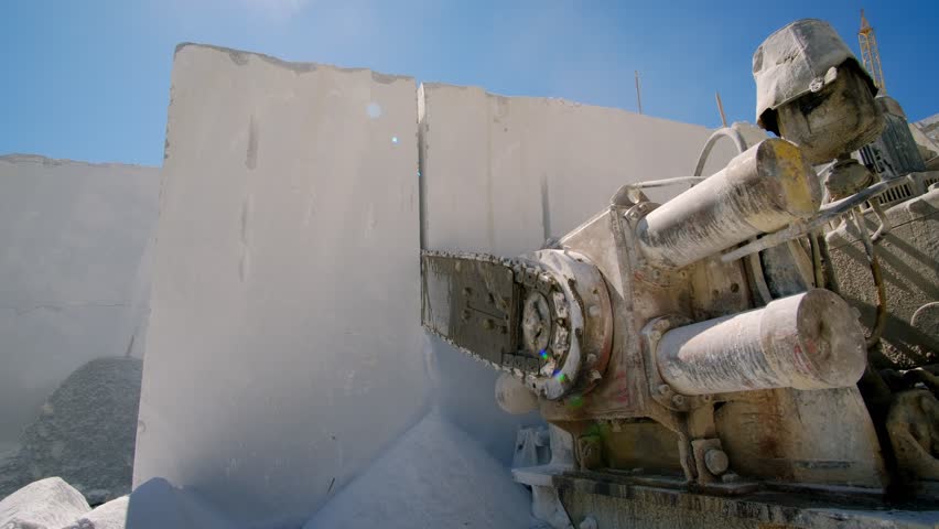 Marble quarry mining, industrial saw cutting rock into large pieces for further processing