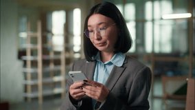 Smiling Asian business woman businesswoman female in office browsing mobile phone internet social media Chinese Korean girl Japanese entrepreneur online chatting message typing smartphone digital bank - Powered by Shutterstock - Get 15% off with code: PIKWIZARD15