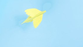 Yellow paper origami dove flies. Blue background. Symbol of peace. Concept of help, support and peace for Ukraine in fight against Russian aggression. Stop motion animation.  - Powered by Shutterstock - Get 15% off with code: PIKWIZARD15