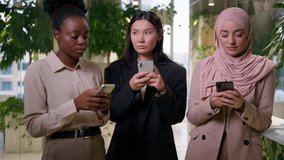 Muslim African businesswomen using mobile phones gadgets addict diverse business women multiracial girls co-workers ignoring Asian colleague shrug shoulders smartphones addiction silence in office - Powered by Shutterstock - Get 15% off with code: PIKWIZARD15