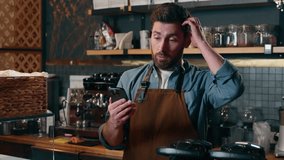 Disappointed Caucasian man barista worker looking screen mobile phone in cafe frustrated guy waiter holding smartphone employee problem business fail online cafeteria male bankruptcy difficulty tech - Powered by Shutterstock - Get 15% off with code: PIKWIZARD15