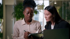 African Asian business partners two diverse girls professional businesswomen Chinese American colleagues co-workers smiling women female teamwork in office managers discuss laptop projects write notes - Powered by Shutterstock - Get 15% off with code: PIKWIZARD15