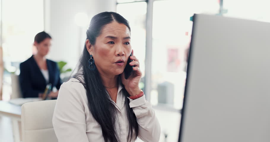 Phone call, office and mature woman on computer with stress for contact, problem solving and discussion. Corporate, business and person on smartphone with network glitch, mistake and crisis online