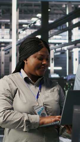 Vertical video Data center engineers performing maintenance on blade server units used for artificial intelligence processing. IT professionals manage data center arrays used for machine learning
