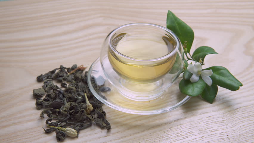 Awesome view of Jasmine green tea in clear cup on wooden table. Healthy flower tea. Fragrant drink.