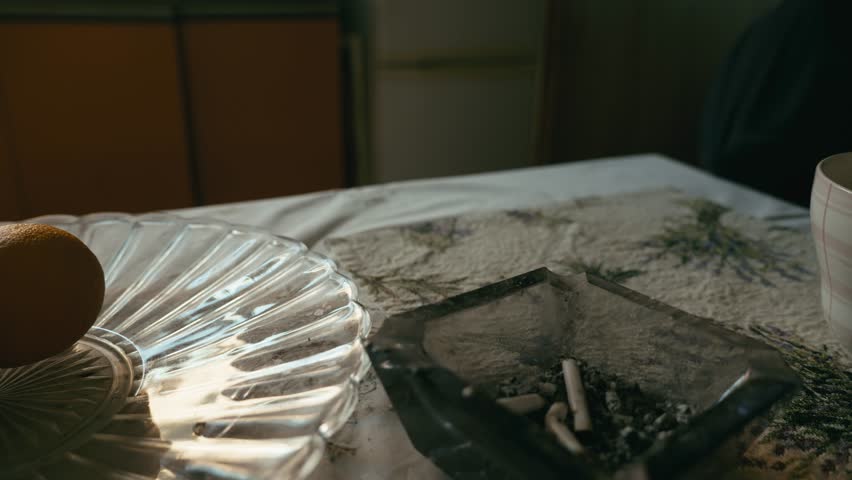 Person smokes cigarette and drinks tea in kitchen MEDIUM SLIDE shot