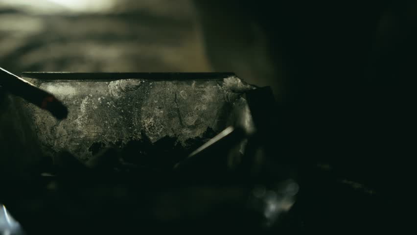Cigarette smouldering in glass ashtray in dark moody light close-up