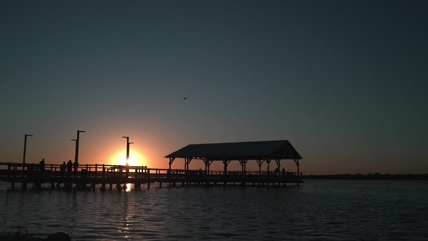 A wide angle of a lake pier and helicopter flying over