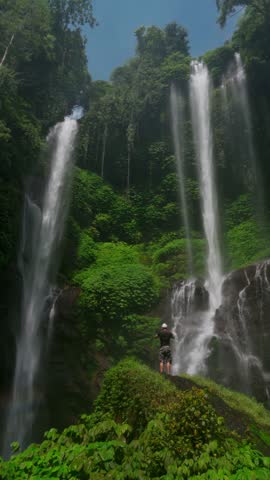 Aerial view of the majestic Sekumpul Waterfall cascading through lush green jungle in Bali, Indonesia.