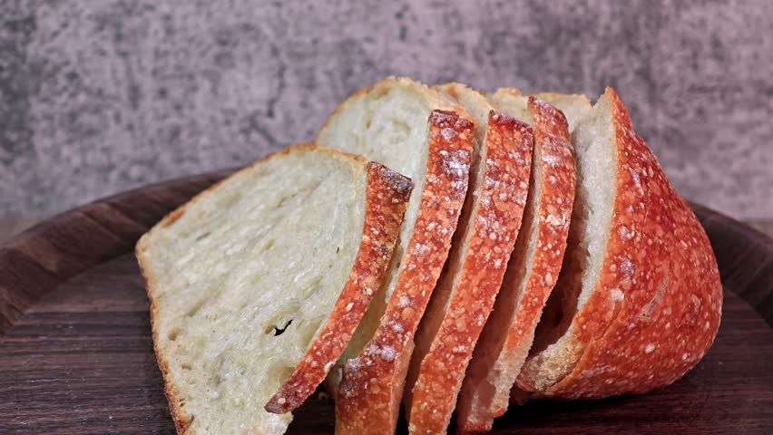 Sliced sourdough bread on wood board, homemade bakery concept.
