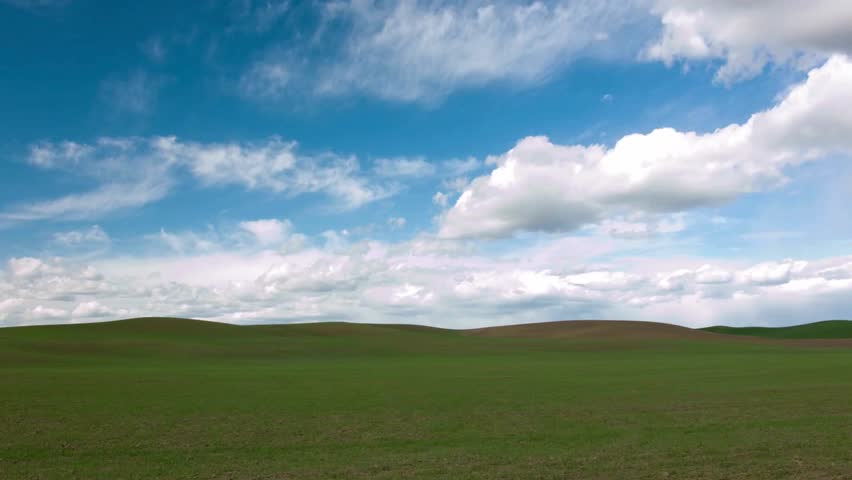 Serene Landscape: Rolling Hills Under a Blue Sky with Fluffy Clouds