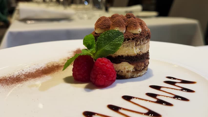 Tiramisu, popular Italian multi-layered dessert close-up with fresh berry and cup of tea. High quality 4k footage
